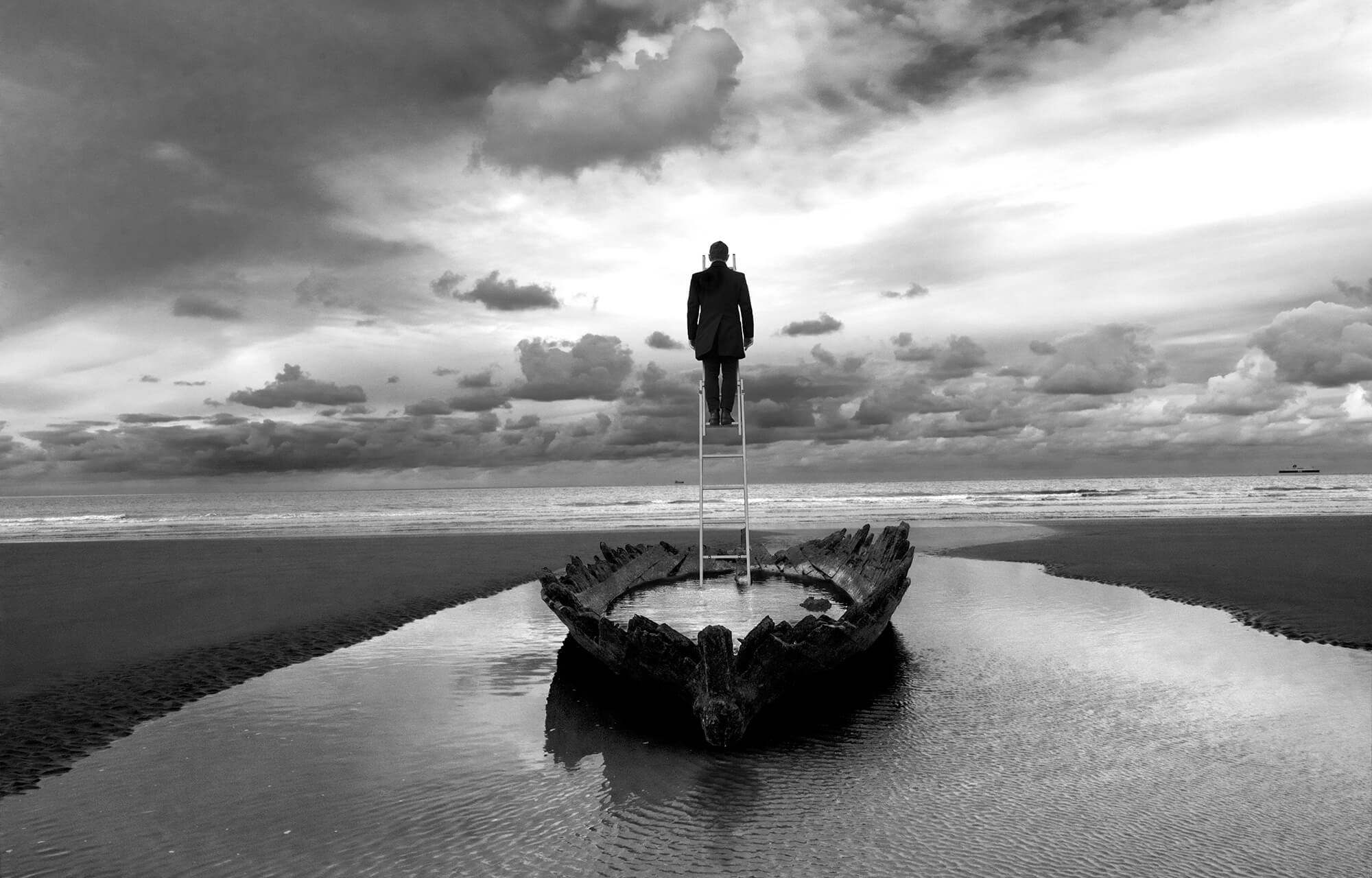 photo art en noir et blanc d'un homme au sommet d'une échelle plantée dans un barque. photo mystérieuse calais florent art