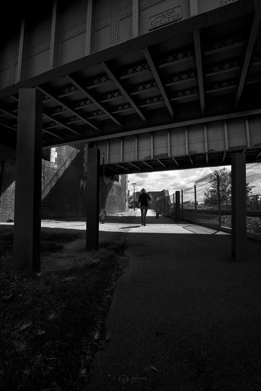 photo art saint omer une femme marche sous les ponts entourée de colonnes noires florent photographe boulogne sur mer lille paris calais marseille