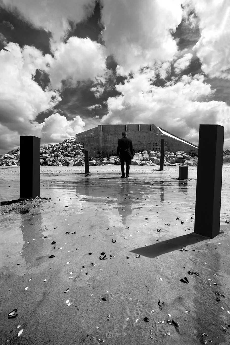 photo art noir et blanc boulogne sur mer d'un homme se refletant à la surface du sable humide entouré de ses colonnes noires face à un blochaus vestige de la guerre hardelot boulogne sur mer lille paris calais marseille florent photographe création