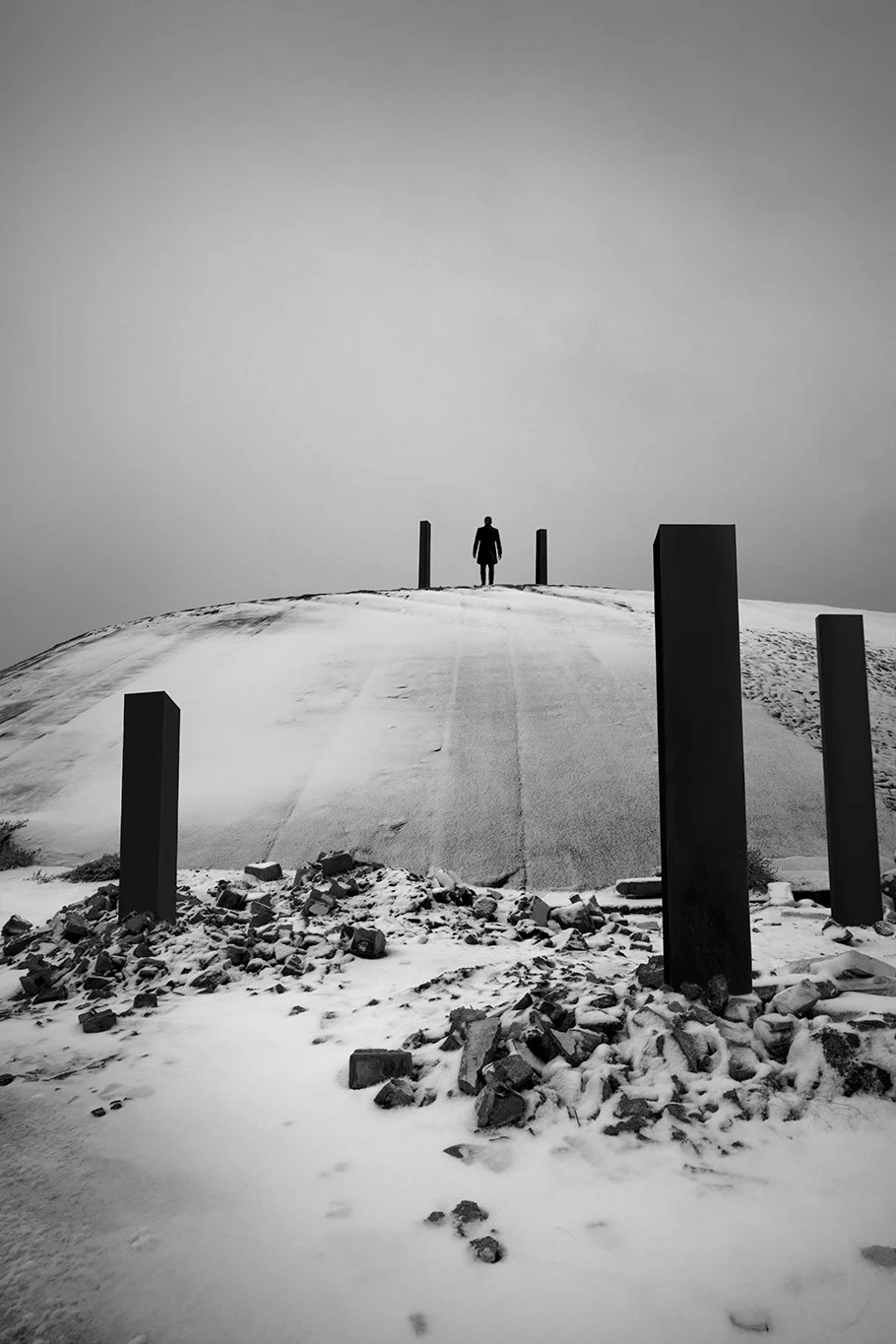 photo art boulogne sur mer noir et blanc d'un homme au sommet d'une digue entouré de ses colonnes noires qui se détachent sur la neige boulogne sur mer Paris