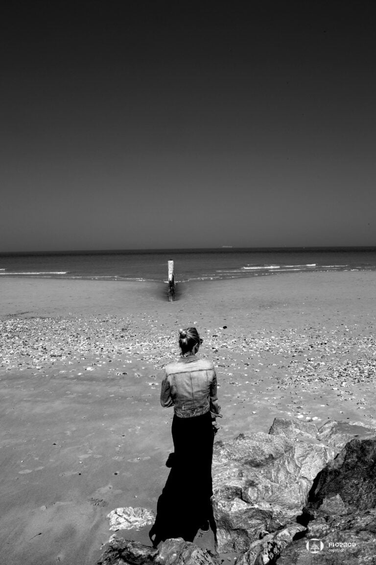 photographe portrait adulte extérieur en noir et blanc graphique d'une jeune femme en noir et blanc face à la mer florent studio boulogne su mer lille le touquet paris