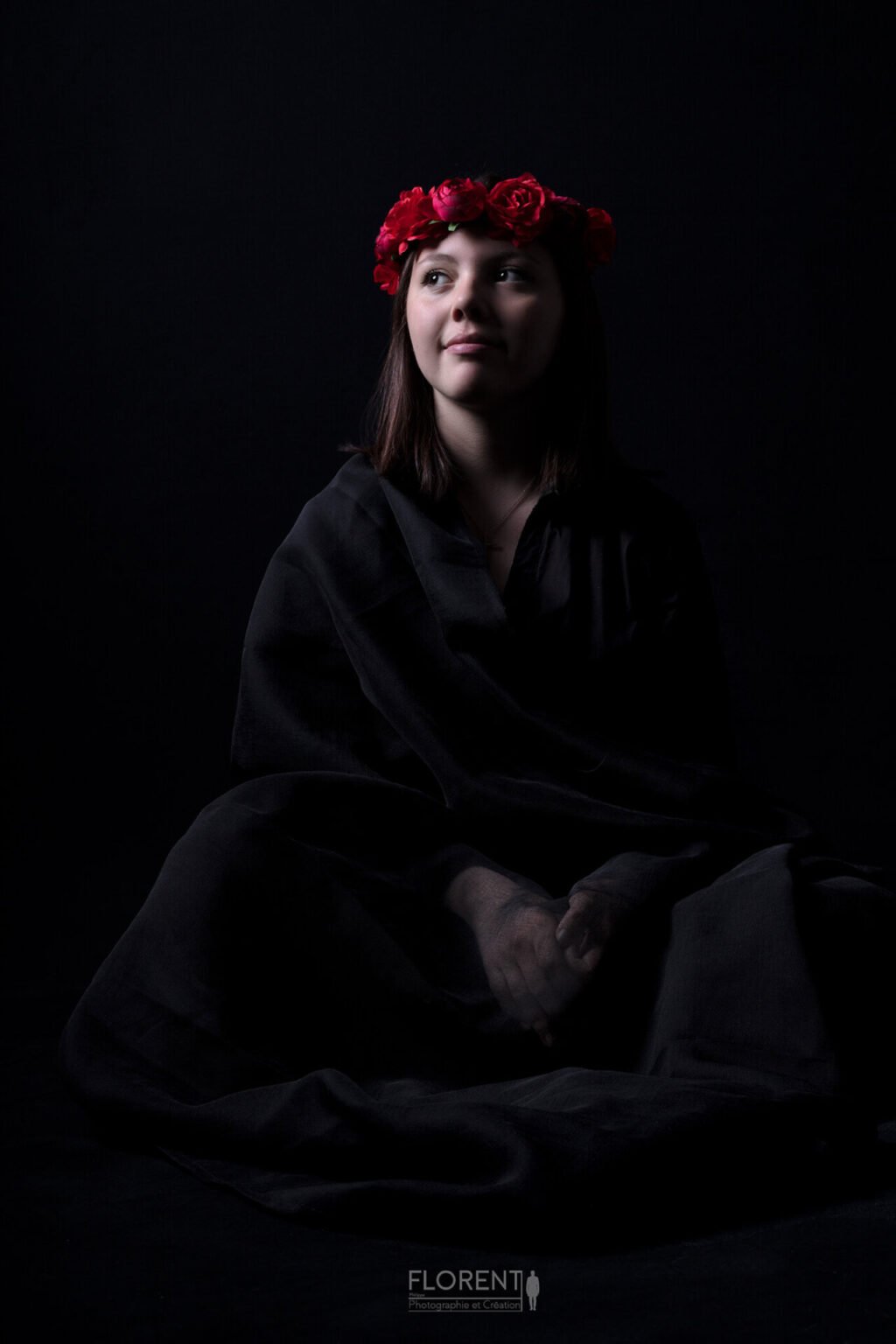 portrait photo en studio d'une jeune fille assise pensive en noire avec couronne de fleurs rouge Boulogne sur mer Lille paris Le Touquet