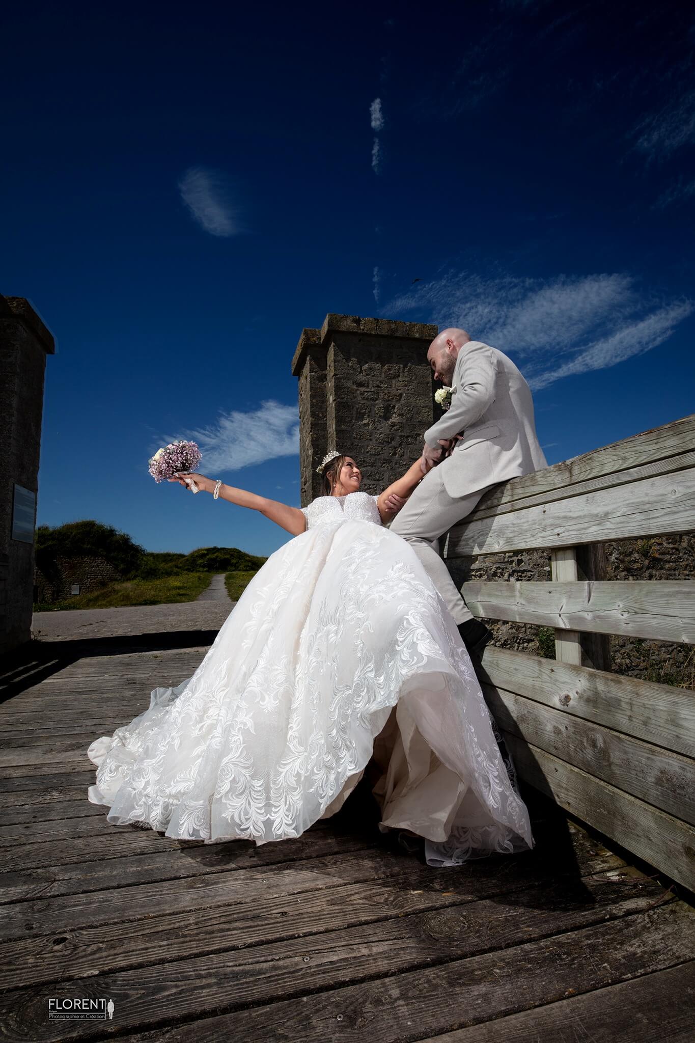photographe mariage Boulogne sur mer mariage humour sur un pont sur fonds de ciel bleu. Florent studio haut de france et toute la france