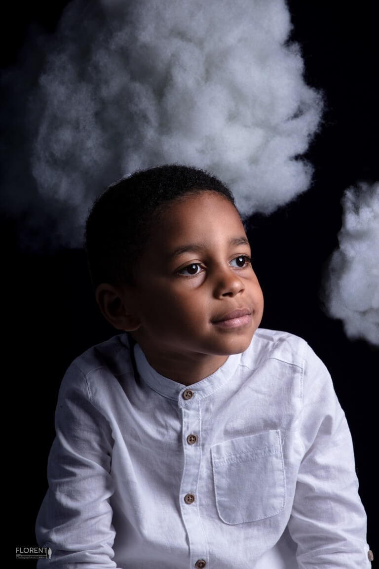 seance photographe enfant en studio photo regardant le décors de nuages magiques studio Florent Photo Boulogne sur mer Lille Paris