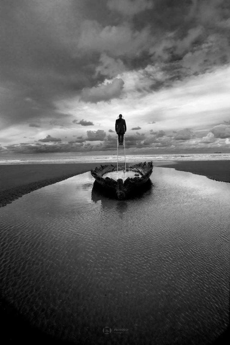 photo art homme en noir de dos sur une echelle plantée dans une barque au milieu de la plage Florent studio art boulogne sur mer lille le touquet paris marseille