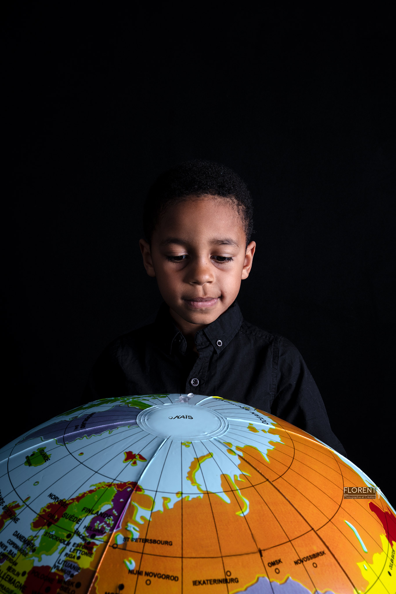 photographe enfant avec pour thème la planète avec ce jeune garçon qui regarde son ballon mappemonde studio Florent Boulogne sur mer