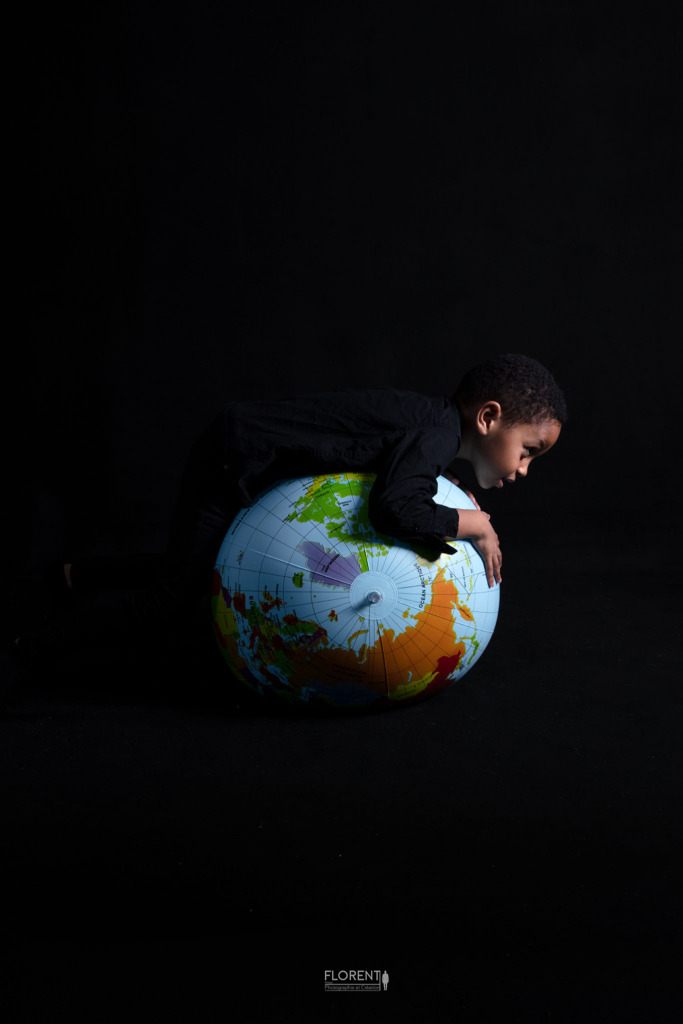 photographe enfant portrait avec pour thème la planète avec ce jeune garçon qui roule sur son ballon mappemonde studio Florent Boulogne sur mer