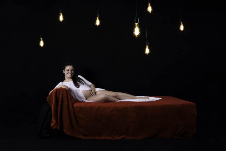 photographe grossesse maternité sur canapé rouge et ampoules en studio Boulogne lille paris