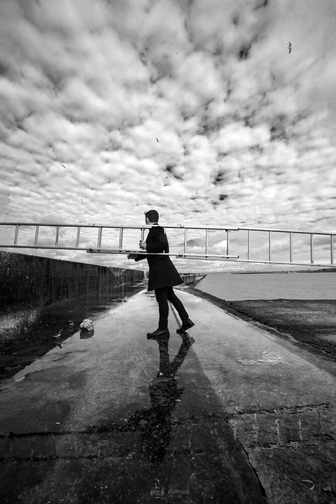 photo art noir et blanc jetée de boulogne sur mer un homme porte une échelledans la tempête florent photographe boulogne sur mer lille paris marseille calais