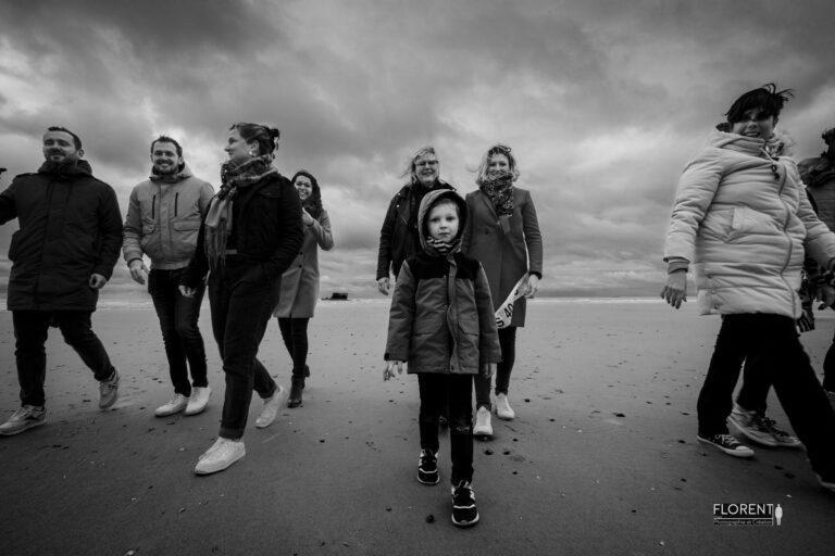 photo noir et blanc anniversaire en bord de mer joyeuse famille et amis se tiennent la main studio florent photographe boulogne sur mer lille le touquet paris Calais