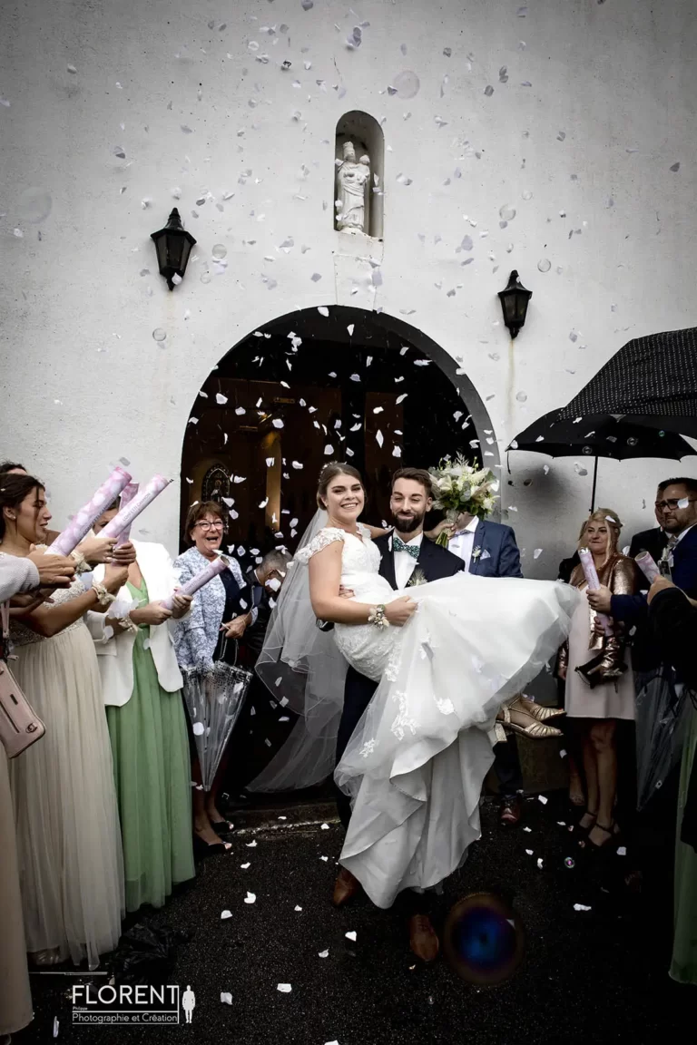 photo émouvante mariage sous la pluie le marié porte sa mariée devant l'église florent studio fanie photographe boulogne sur mer lille calais saint omer le touquet paris france