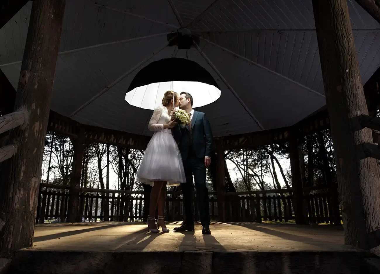 photographe mariage sous le kiosque s'embrassent sous le parapluie lumineux florent studio lille paris boulogne sur mer saint omer