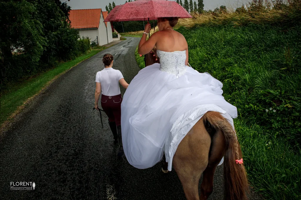mariee-saint-omer-a-cheval-et-parapluie-avec-ecuilleres-sous-lorage-florent-studio-photographe-mariage-pas-de-calais-nord-boulogne-sur-mer-lille-paris-hardelot-arras-le-touquet.webp