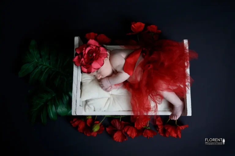 photo bébé dans petit lit avec fleurs et habits rouge dort paisiblement fanie photographe florent studio boulogne sur mer lille le touquet paris calais saint omer berck