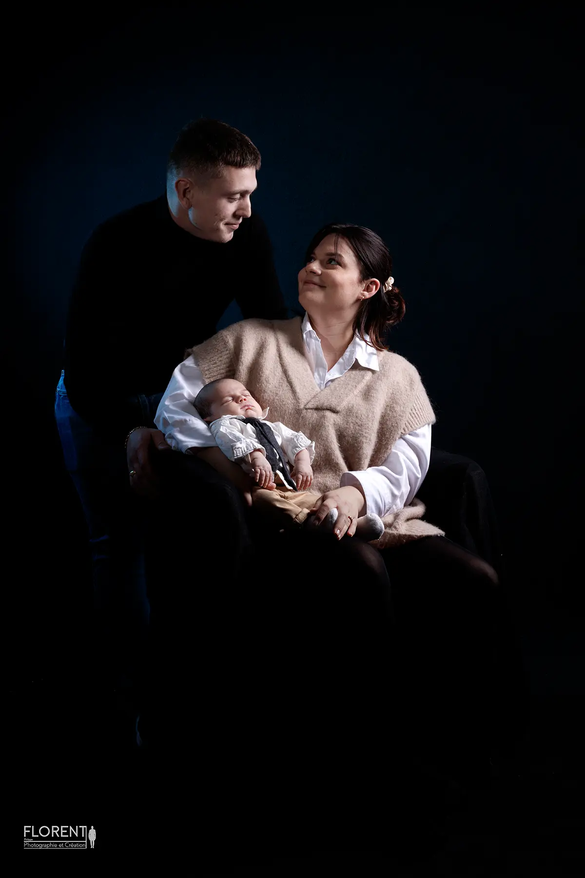 photographe bebe saint omer bebe dans les bras de maman assise et papa tendre sur florent studio fanie photographe boulogne sur mer lille le touquet