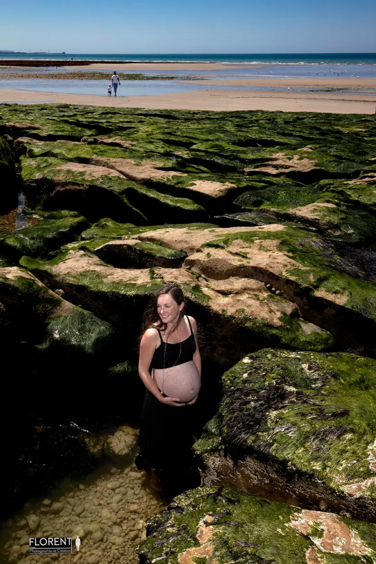 photographe maternite grossesse plage dans l eau au milieu des rochers famille au loin florent studio fanie photographe boulogne sur mer lille le touquet berck paris saint omer calais